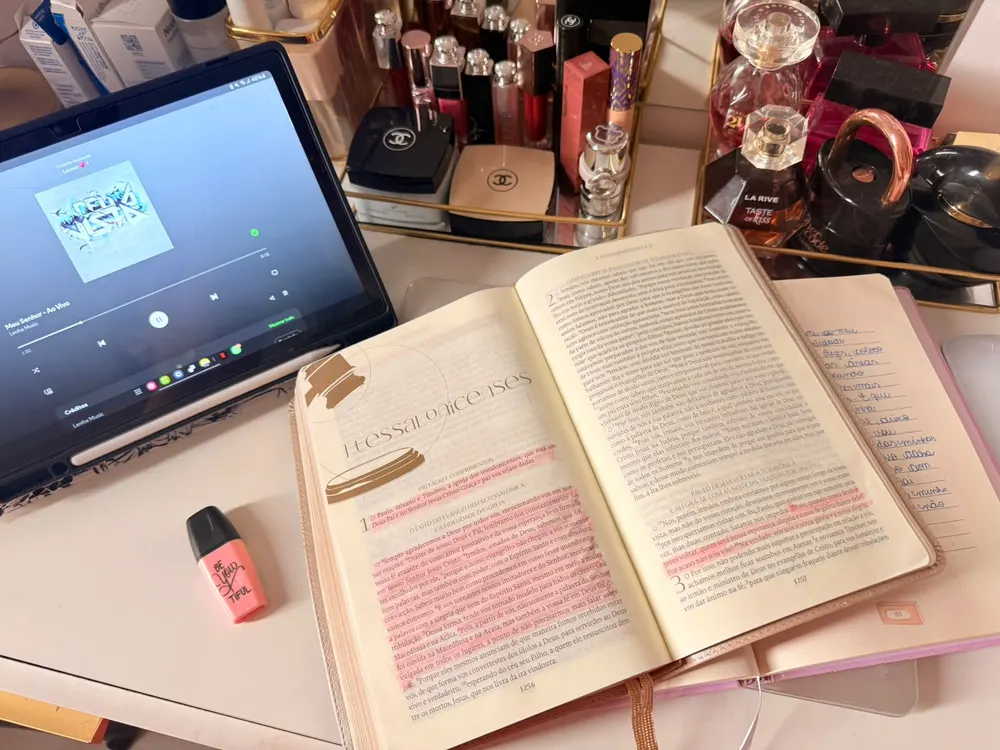 Bíblia em Tessalonicenses com trechos marcados e louvor tocando no tablet